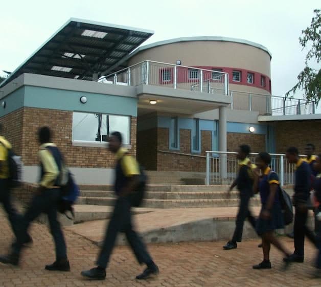 Learners walking towards a newly completed school building.